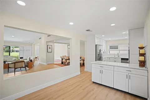 a large white kitchen with white cabinets and wooden floor