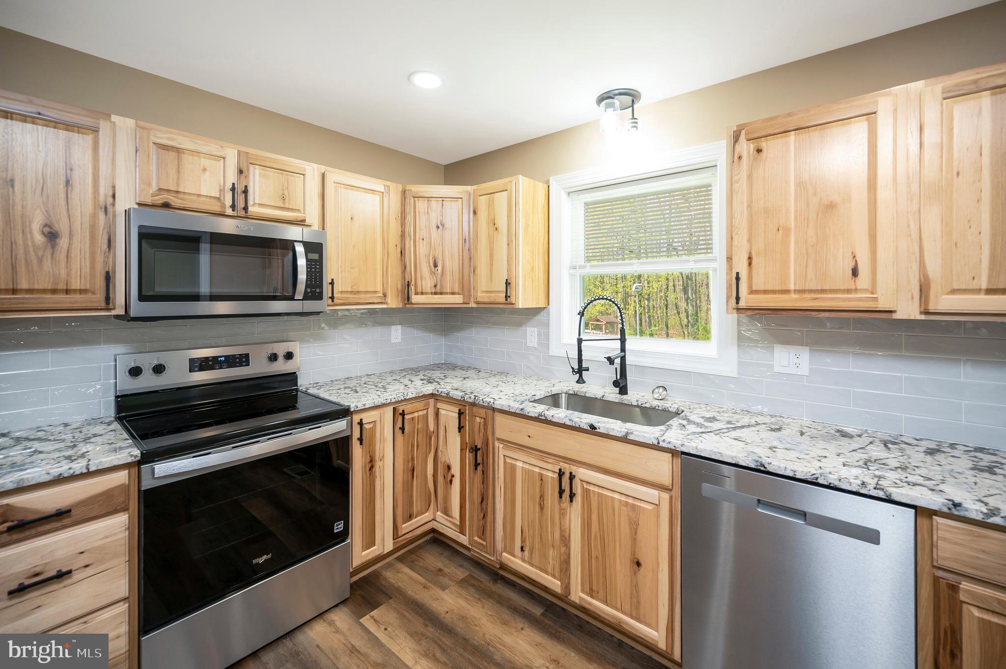 13452 Post Oak Road Spotsylvania, VA 22551 - Photo 27 of 56 a kitchen with granite countertop a sink cabinets stainless steel appliances and a window