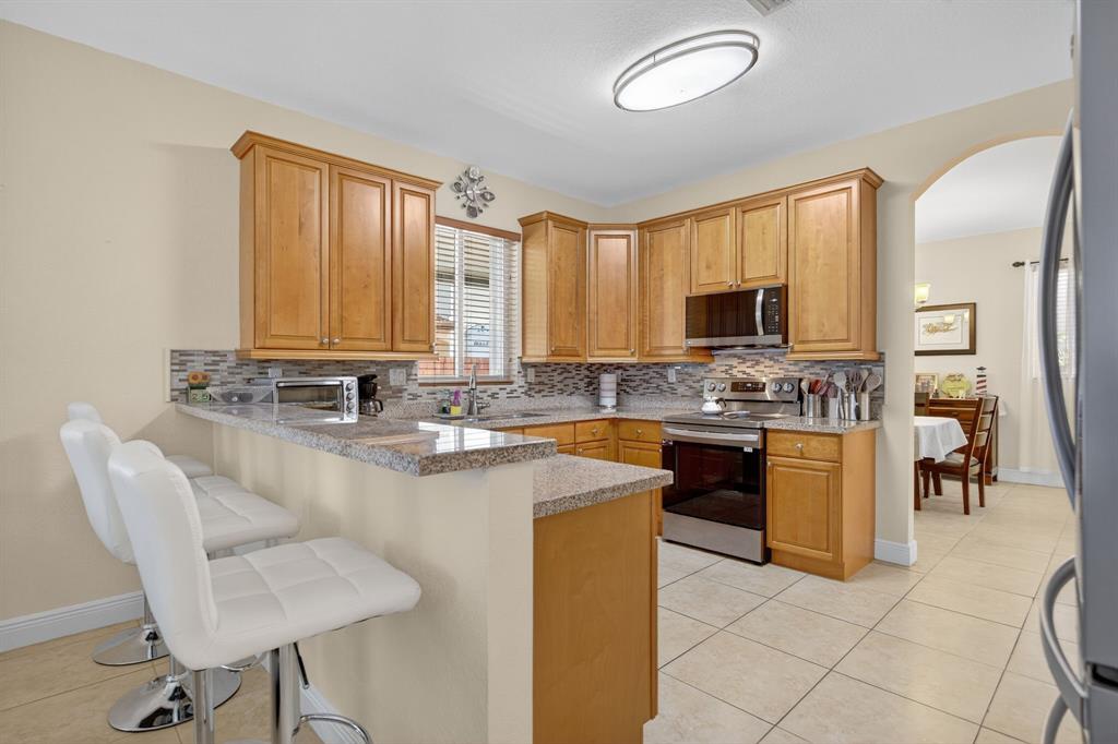 18203 Southwest 152nd Place Miami, FL 33187 - Photo 21 of 55 a large kitchen with kitchen island granite countertop a stove a sink a dining table and chairs