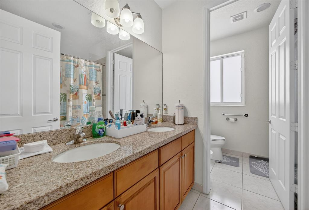 18203 Southwest 152nd Place Miami, FL 33187 - Photo 30 of 55 a bathroom with a granite countertop double vanity sink a mirror and a shower