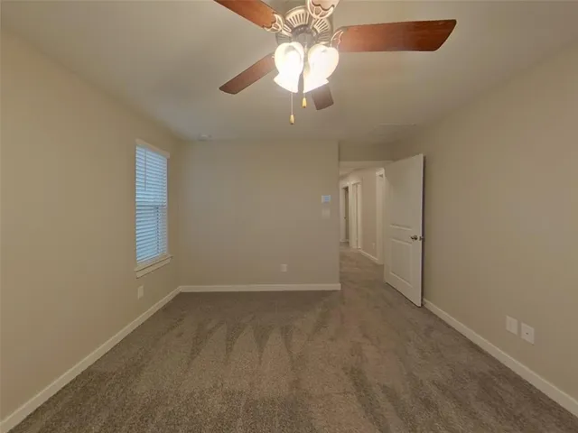 an empty room with a chandelier fan and windows