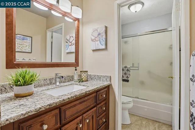 a bathroom with a granite countertop sink a toilet and shower