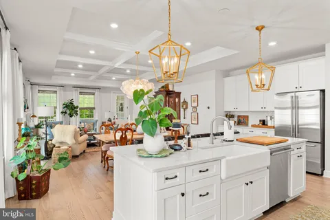 a kitchen with sink stove and white cabinets with wooden floor