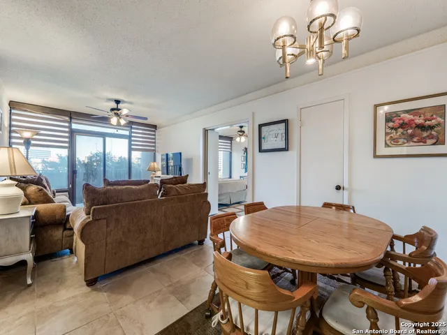 a living room with furniture a chandelier and a dining table