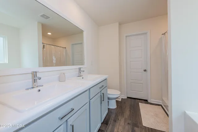 a bathroom with a double vanity sink toilet and shower