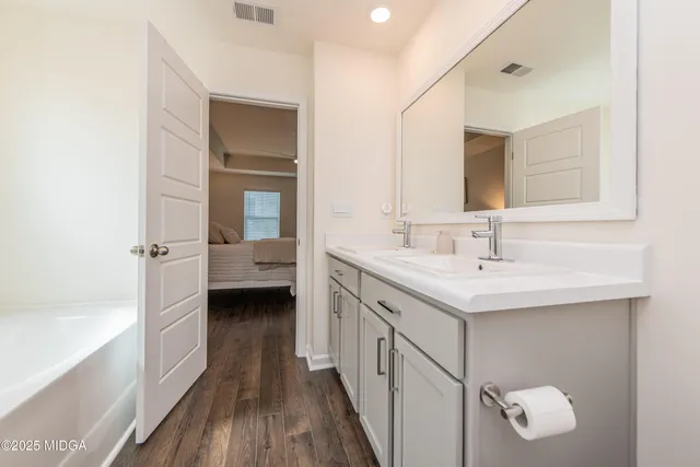 a bathroom with a double vanity sink a mirror and a bathtub