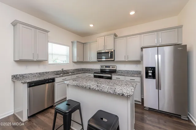 a kitchen with stainless steel appliances granite countertop a refrigerator a stove a sink and a microwave