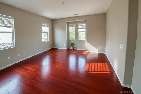 an empty room with wooden floor and windows