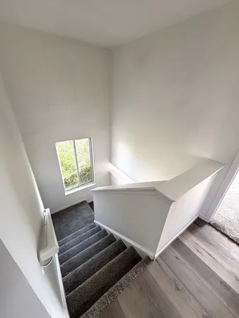 a view of an empty room with wooden floor and stairs