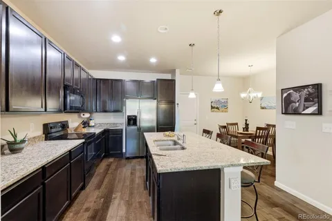 a kitchen with granite countertop cabinets a sink stainless steel appliances and wooden floor