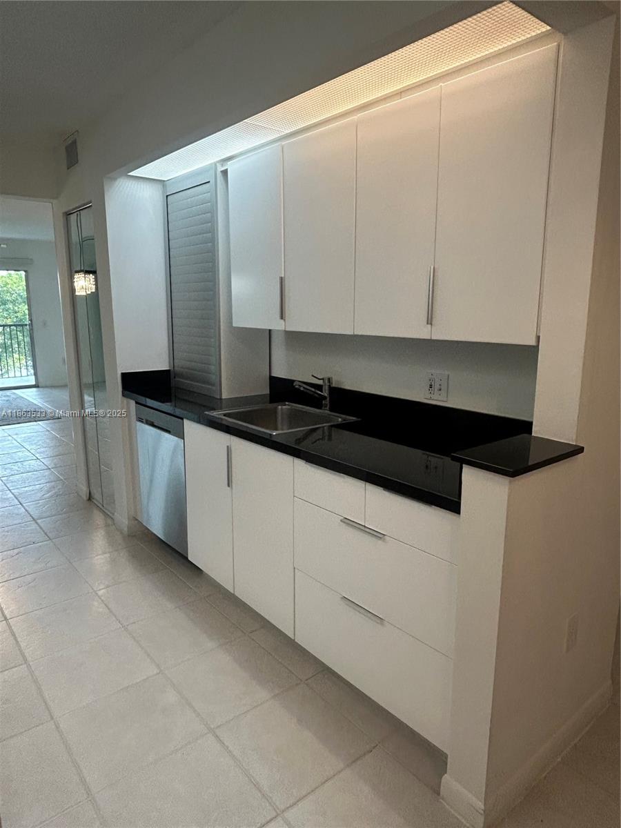 901 Southwest 141st Avenue, Unit 409M Pembroke Pines, FL 33027 - Photo 2 of 10 a kitchen with granite countertop white cabinets and sink