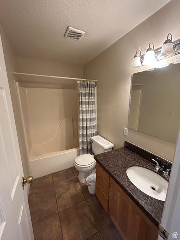 432 Spring Lane Logan, UT 84341 - Photo 21 of 22 Bathroom featuring vanity, a textured ceiling, shower / bath combo, dark tile patterned flooring, and a textured wall