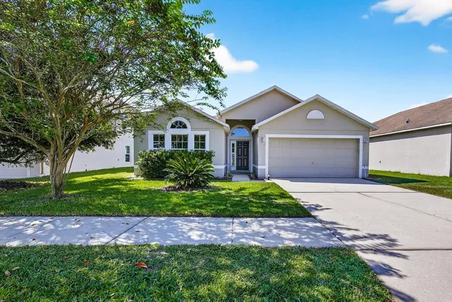 a front view of a house with a garden and trees