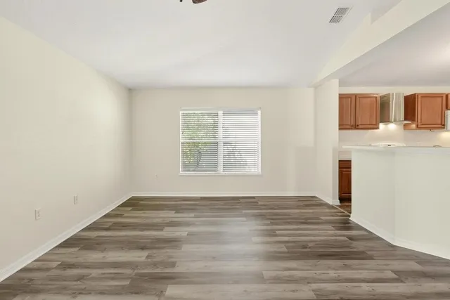 a view of empty room with wooden floor and fan