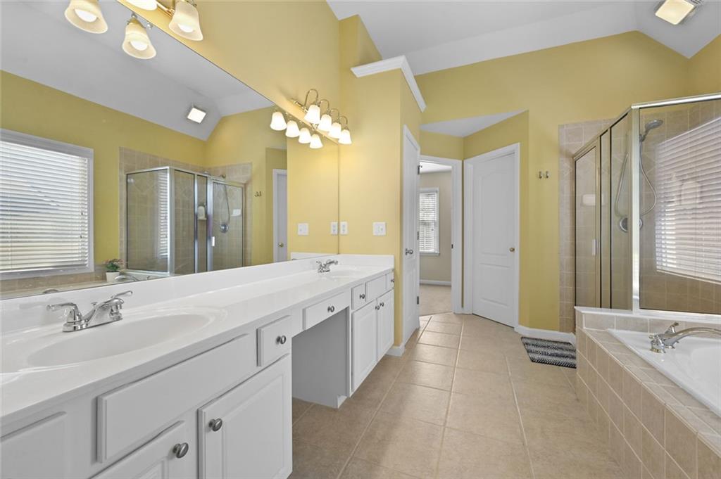 3945 Summit Gate Drive Suwanee, GA 30024 - Photo 33 of 45 a spacious bathroom with a double vanity sink a large mirror and a bathtub
