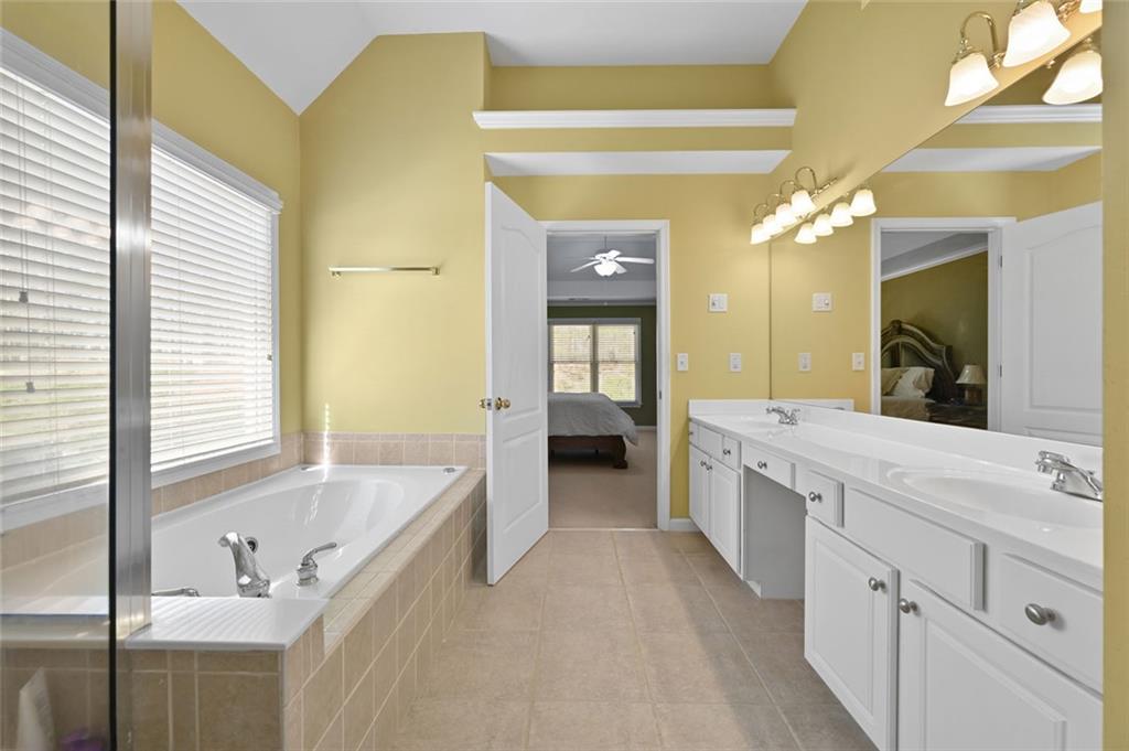 3945 Summit Gate Drive Suwanee, GA 30024 - Photo 34 of 45 a large bathroom with a tub a double vanity sink and a large mirror