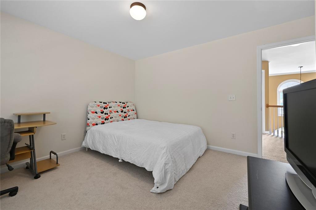 3945 Summit Gate Drive Suwanee, GA 30024 - Photo 40 of 45 a bedroom with a bed and a flat tv screen on the dresser