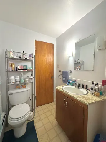 a bathroom with a granite countertop toilet a sink and a mirror