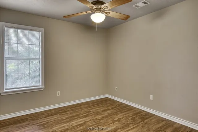 a view of an empty room with window and chandelier fan