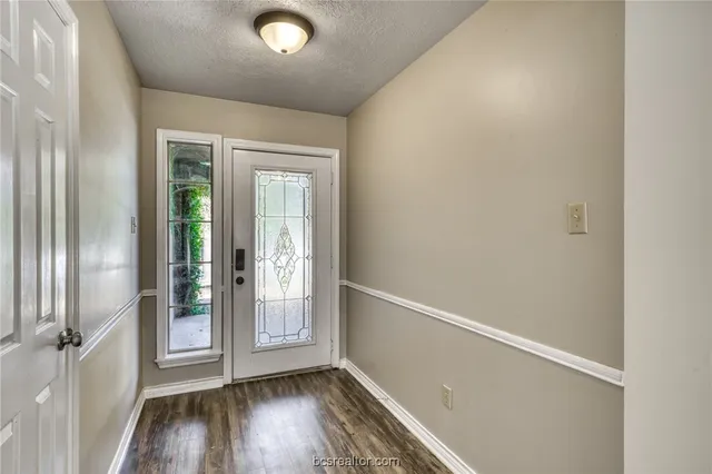 a view of an empty room with wooden floor fireplace and a window