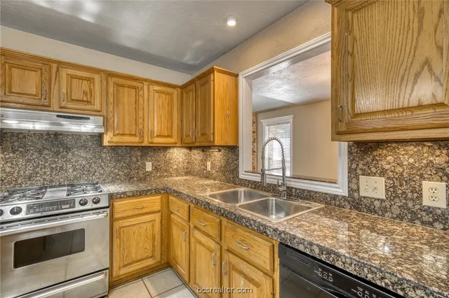 a kitchen with stainless steel appliances granite countertop a stove refrigerator and cabinets