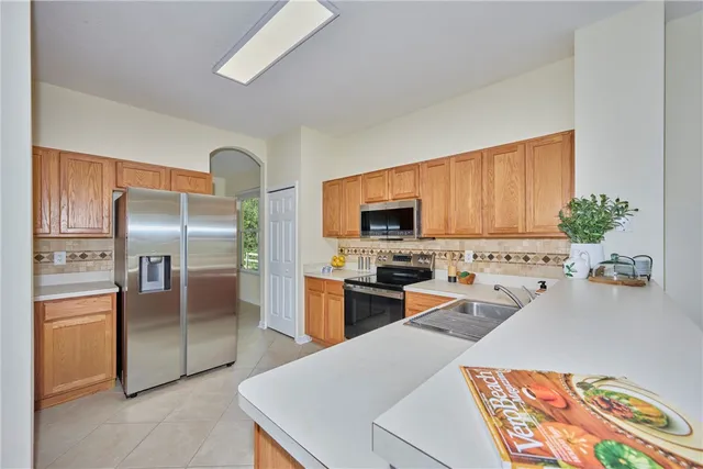 a kitchen with stainless steel appliances kitchen island granite countertop a refrigerator oven a sink dishwasher and wooden cabinets with wooden floor