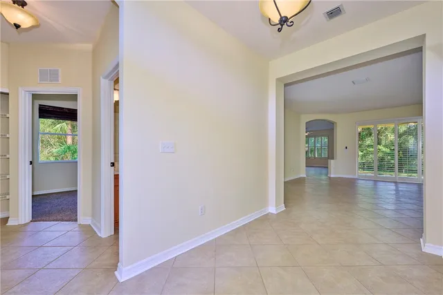 a view of a hallway to an empty room with wooden floor and a fireplace
