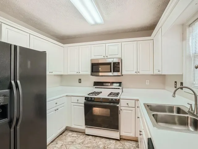 a kitchen with stainless steel appliances granite countertop a refrigerator stove and sink