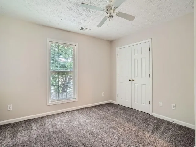 an empty room with windows and fan