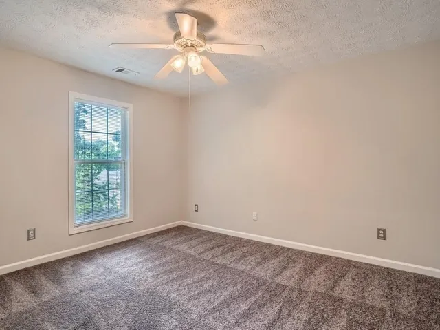 an empty room with windows and fan