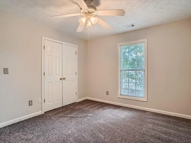 an empty room with windows and fan