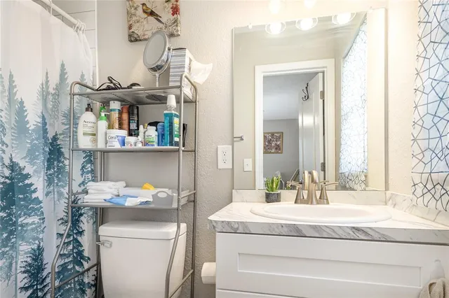 a bathroom with a granite countertop sink a toilet and a mirror