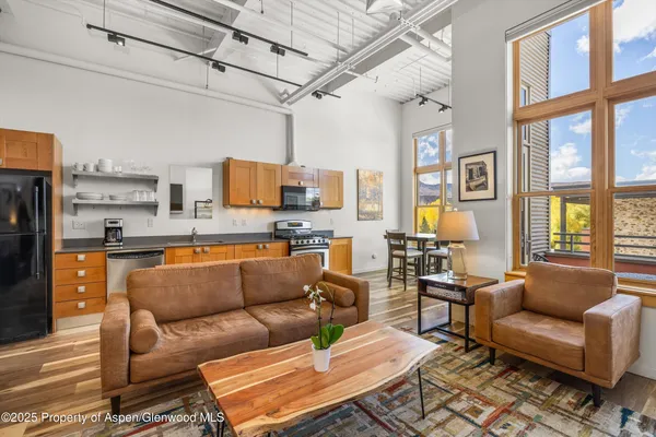 a living room with furniture a rug and kitchen view