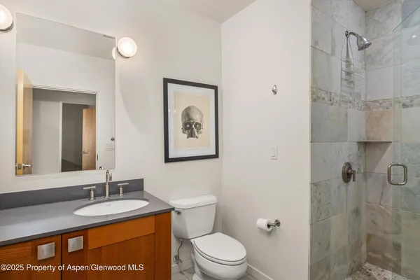 a bathroom with a granite countertop toilet sink mirror and shower