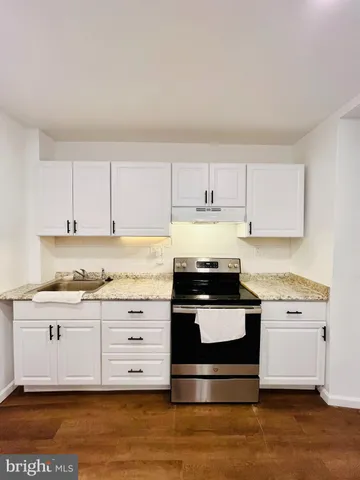 a kitchen with stainless steel appliances granite countertop a stove a sink and white cabinets