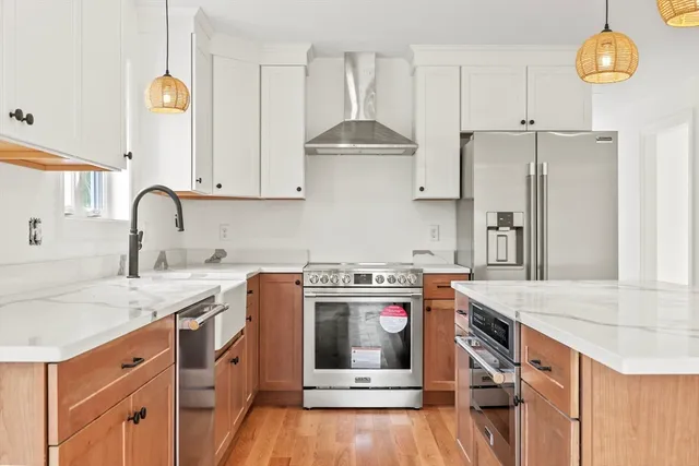 a kitchen with stainless steel appliances granite countertop a stove a sink dishwasher and white cabinets with wooden floor