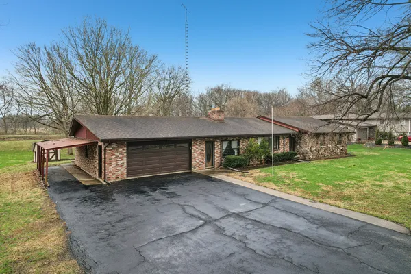 a view of a house with a yard and large tree