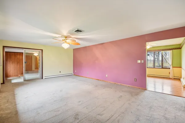 an empty room with chandelier fan and windows