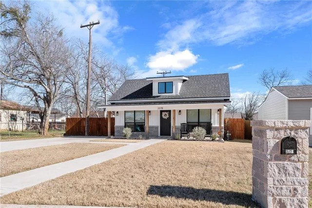 a front view of a house with a yard covered with snow and a tree