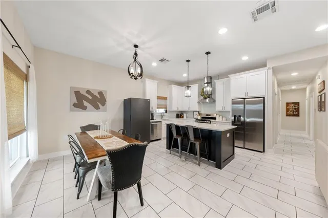 a kitchen with stainless steel appliances kitchen island granite countertop a table chairs and a sink