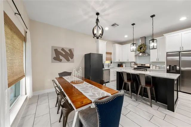 a kitchen with stainless steel appliances kitchen island granite countertop a stove a refrigerator a sink a dining table and chairs with wooden floor