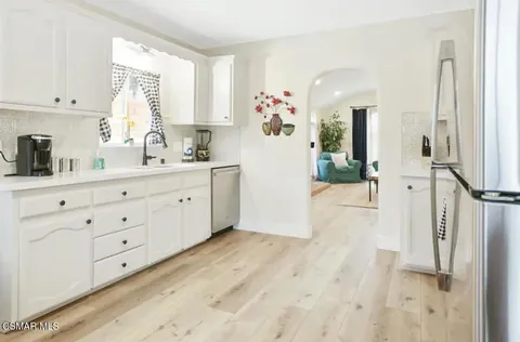 a hallway with white cabinets and wooden floor
