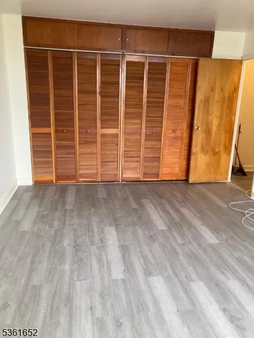 a view of an empty room with wooden floor and a cabinet