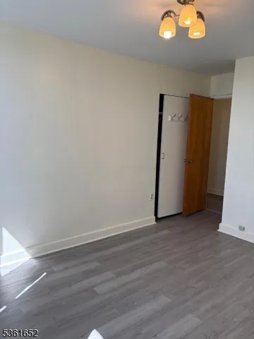 a view of an empty room with wooden floor and window