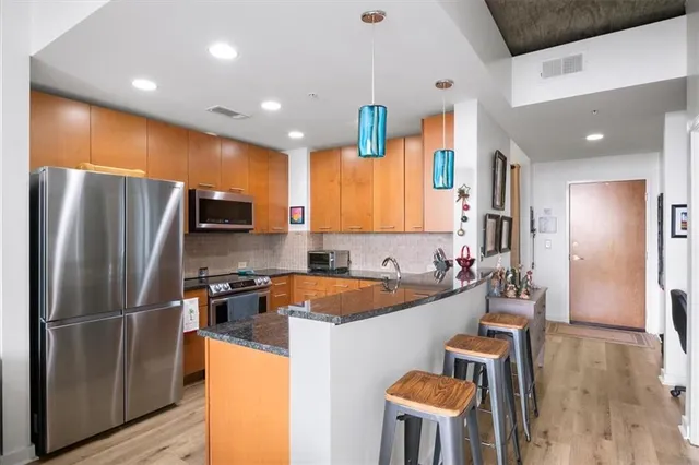 a kitchen with stainless steel appliances a refrigerator a sink a stove a dining table and chairs