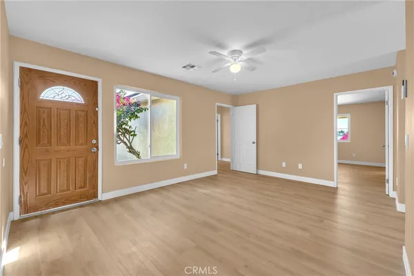 a view of an empty room with window and wooden floor
