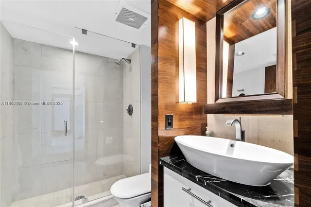 a bathroom with a sink a toilet a mirror and shower
