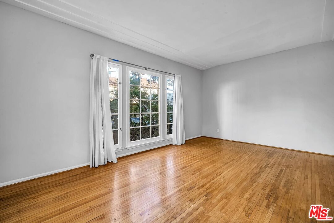 9000 Burton Way Beverly Hills, CA 90211 - Photo 25 of 26 a view of an empty room with wooden floor and a window