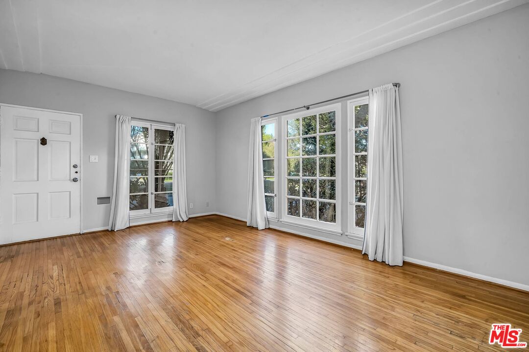 9000 Burton Way Beverly Hills, CA 90211 - Photo 4 of 26 a view of an empty room with wooden floor and windows