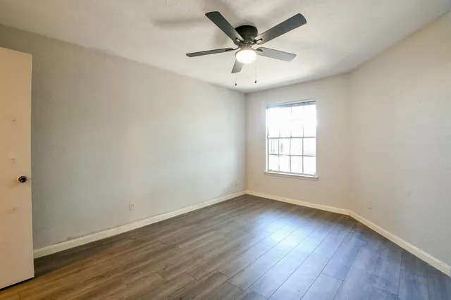 an empty room with wooden floor and windows